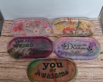 May include: A collection of five oval resin trays with various designs and text. The trays feature dried flowers, glitter, and inspirational quotes like "You are Awesome" and "If you can dream, you can do it."