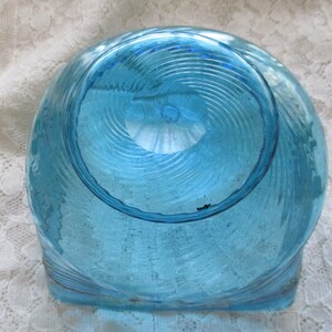 May include: A blue glass bowl with a swirl design. The bowl is clear and has a textured surface.