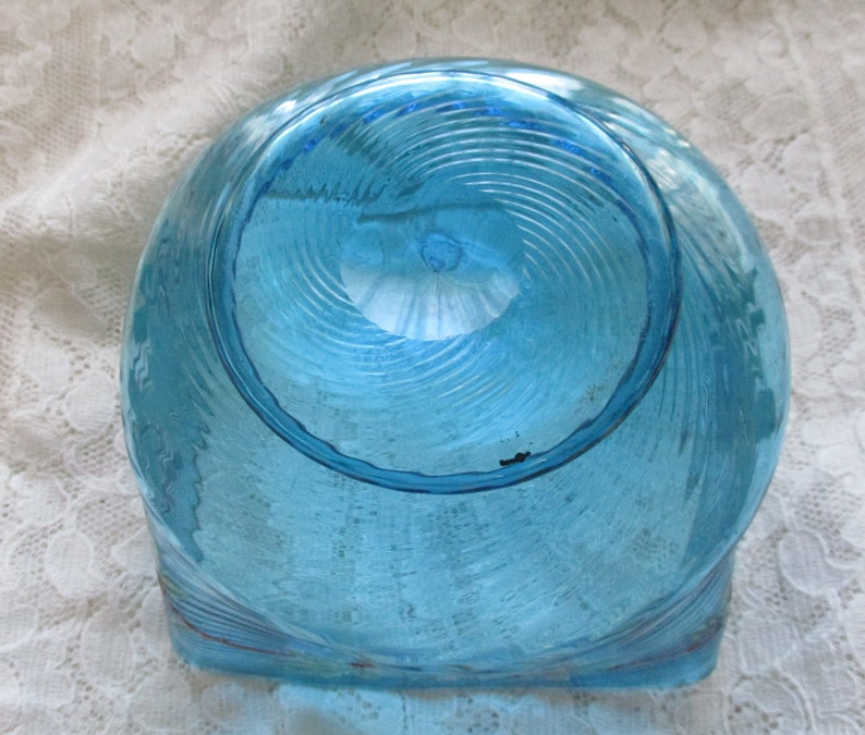 May include: A blue glass bowl with a swirl design. The bowl is clear and has a textured surface.