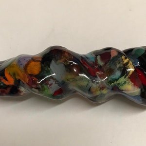 以下が含まれることがあります： 渦巻き状のカラフルなデザインが施された黒いガラスパイプ。パイプの長さは約15cmで、片側に小さなボウルがあります。