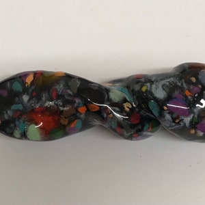 以下が含まれることがあります： 黒くねじれたセラミックパイプで、斑点のあるマルチカラーの釉薬がかかっています。釉薬はオレンジ、赤、緑、青、紫の色合いを特徴としています。