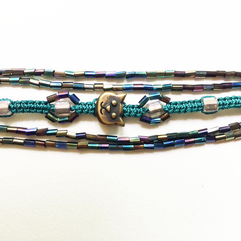 Macrame bracelet with brass cat charm and glass rainbow tube and seed beads and square light pink glass beads