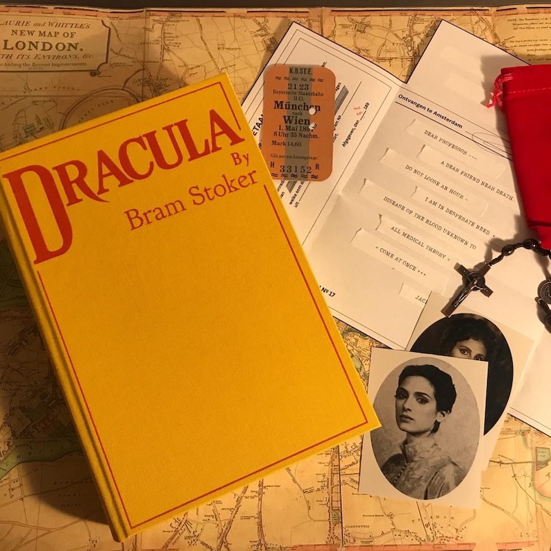 K&ouml;nnte beinhalten: Ein gelbes gebundenes Buch mit dem Titel Dracula von Bram Stoker, eine alte Fahrkarte von M&uuml;nchen nach Wien, ein bedruckter Brief mit Text, ein schwarzer Rosenkranz mit Kreuz, ein roter Stoffbeutel und ein Schwarz-Wei&szlig;-Portr&auml;tfoto einer Person.