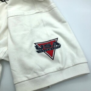 Pu&ograve; includere: Maglietta bianca a maniche corte con un logo USA Track & Field rosso, bianco e blu sulla manica.