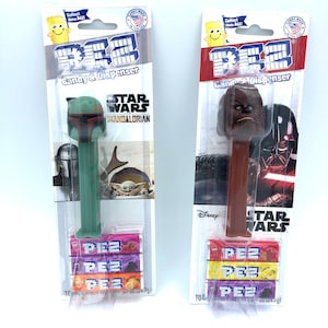 Peut inclure: Deux distributeurs de bonbons Pez sur le thème de Star Wars avec des recharges de bonbons. Le distributeur de gauche représente Boba Fett de The Mandalorian et le distributeur de droite représente Chewbacca. Les deux distributeurs portent le logo Star Wars et le logo Pez.
