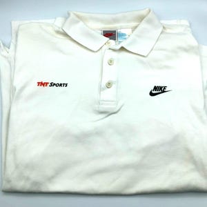 Pu&ograve; includere: Polo a maniche lunghe bianca con logo Nike nero e "TNT Sports" ricamato sul davanti.