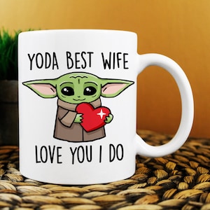 Puede incluir: Taza de cer&aacute;mica blanca con una imagen de dibujos animados de un extraterrestre verde sosteniendo un coraz&oacute;n rojo. El texto "YODA BEST WIFE LOVE YOU I DO" est&aacute; impreso en la taza.
