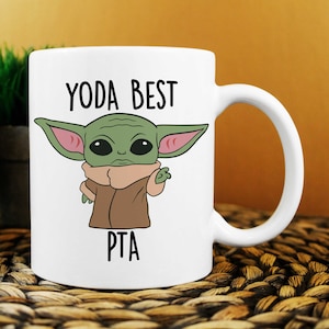 May include: White ceramic mug featuring a green cartoon character and the text "YODA BEST PTA".