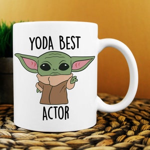 Puede incluir: Taza de cer&aacute;mica blanca con un personaje de dibujos animados verde y el texto "YODA BEST ACTOR".