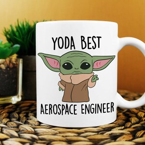 May include: White ceramic mug with a cartoon image of a green alien character with large ears and a brown robe. The text "YODA BEST AEROSPACE ENGINEER" is printed on the mug.