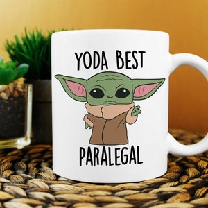 May include: White ceramic mug with a cartoon image of a green alien character with large ears and the text "YODA BEST PARALEGAL".