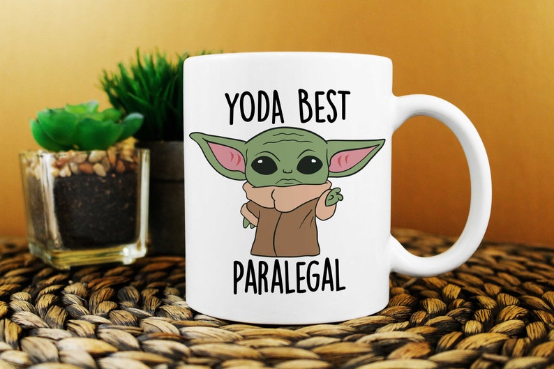 May include: White ceramic mug with a cartoon image of a green alien character with large ears and the text "YODA BEST PARALEGAL".