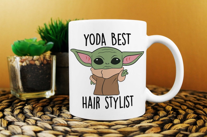 May include: White ceramic mug with a green cartoon character with large ears and the text "YODA BEST HAIR STYLIST" printed on it.