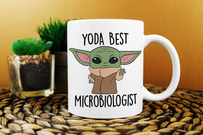 May include: White ceramic mug with a green cartoon character and the text "YODA BEST MICROBIOLOGIST".