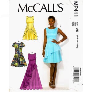 May include: McCall's sewing pattern MP411 size A5 for dresses. The envelope displays four dress variations: a sleeveless yellow knee-length dress, a short-sleeved floral print dress, a sleeveless light blue dress, and a long purple dress with ruffles.