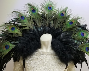 May include: A black and green feather shoulder piece with peacock feathers. The feathers have blue eyes.