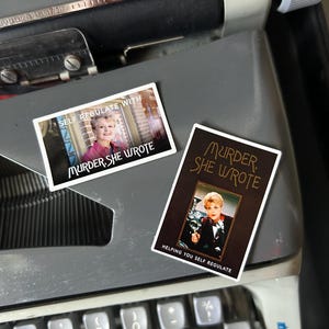 Puede incluir: Dos pegatinas rectangulares con Angela Lansbury de Murder, She Wrote. Una pegatina es horizontal con el texto "SELF REGULATE WITH MURDER, SHE WROTE". La otra es vertical con el texto "MURDER, SHE WROTE" y "HELPING YOU SELF REGULATE".