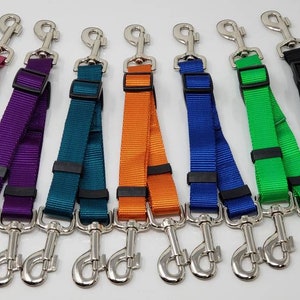 May include: Eight dog leash couplers in different colors, including pink, purple, teal, orange, blue, green, and black. Each coupler has two silver clips.