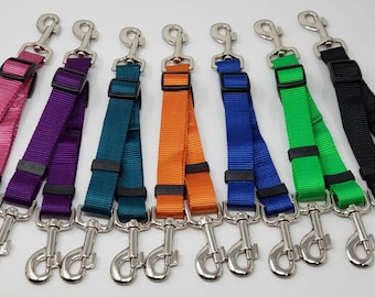 May include: Eight dog leash couplers in different colors, including pink, purple, teal, orange, blue, green, and black. Each coupler has two silver clips.