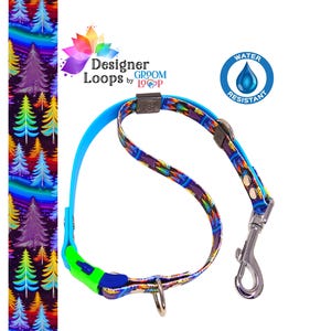 May include: A blue and multi-colored dog collar with a rainbow tree pattern. The collar has a blue buckle and a silver clip. The text "Designer Loops by Groom Loop" is visible on the collar. The text "Water Resistant" is visible in a blue circle with a water drop.