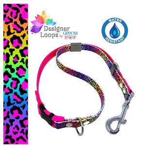May include: A pink and rainbow leopard print dog collar and leash set with a silver clasp. The collar and leash are water resistant and feature the text "Designer Loops by Groom Loop".