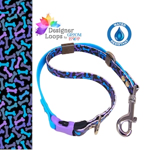May include: A blue and purple dog collar with a bone pattern and a matching leash. The collar has a purple buckle and the leash has a silver clip. The text "Designer Loops by Groom Loop" is printed on the collar. The text "Water Resistant" is printed on a blue circle with a water drop.