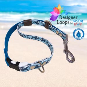 May include: A blue and white dog collar and lead set featuring an orca pattern. The lead has a silver metal clasp and a blue rubber handle. The collar has a black plastic buckle. The text "Designer Loops by Groom Loop" is visible.