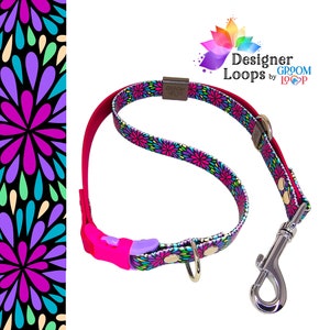 May include: A pink and black dog leash with a floral pattern and a silver clip. The leash is made by Designer Loops by Groom Loop.