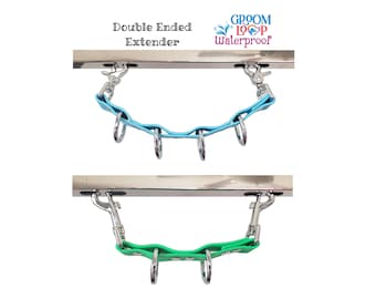 May include: Double ended extender for a dog leash, shown in two colors: light blue and green. The extender is made of a rubber material and has metal hooks on each end. The text "Groom Loop Waterproof" is printed on a silver bar.