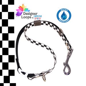 May include: A black and white checkered dog grooming loop with a silver clasp and ring. The loop is water-resistant and features the text "Designer Loops by Groom Loop".
