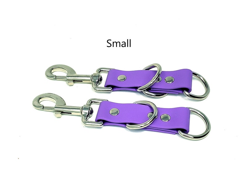 May include: Two purple leather straps with silver metal rings and clips. The straps are labeled "Small".