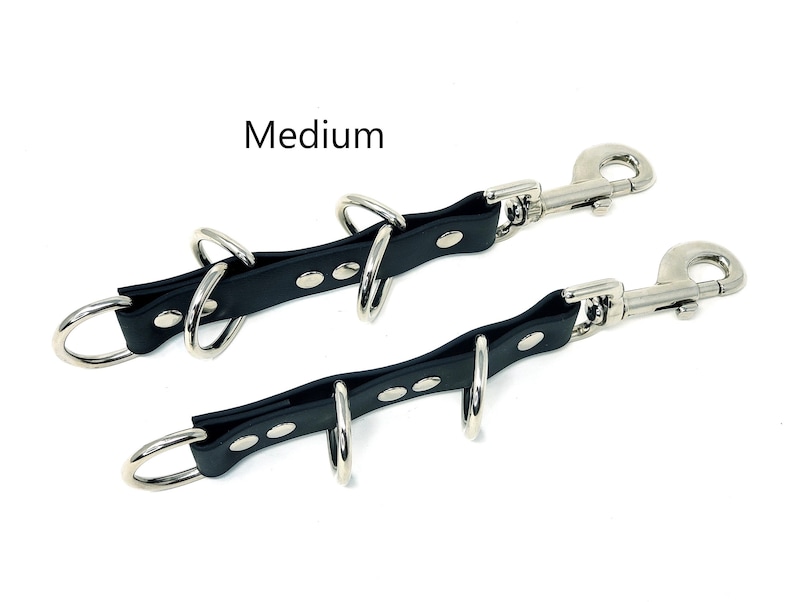 May include: Black leather leash with two metal swivel clips and four metal rings. The leash is labeled "Medium".