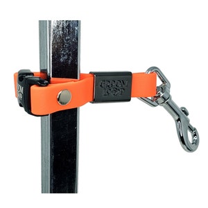 May include: Orange and black dog lead with a metal clip and the words "Groom Loop" printed on the strap.