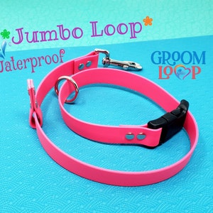 May include: Pink waterproof dog collar and leash set with a black buckle and silver hardware. The collar and leash are labeled "Jumbo Loop" and "Groom Loop".