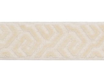 May include: Cream-colored fabric trim with a repeating geometric pattern. The trim has a soft, textured appearance and a subtle sheen. The design features interlocking shapes, creating a visually interesting border.