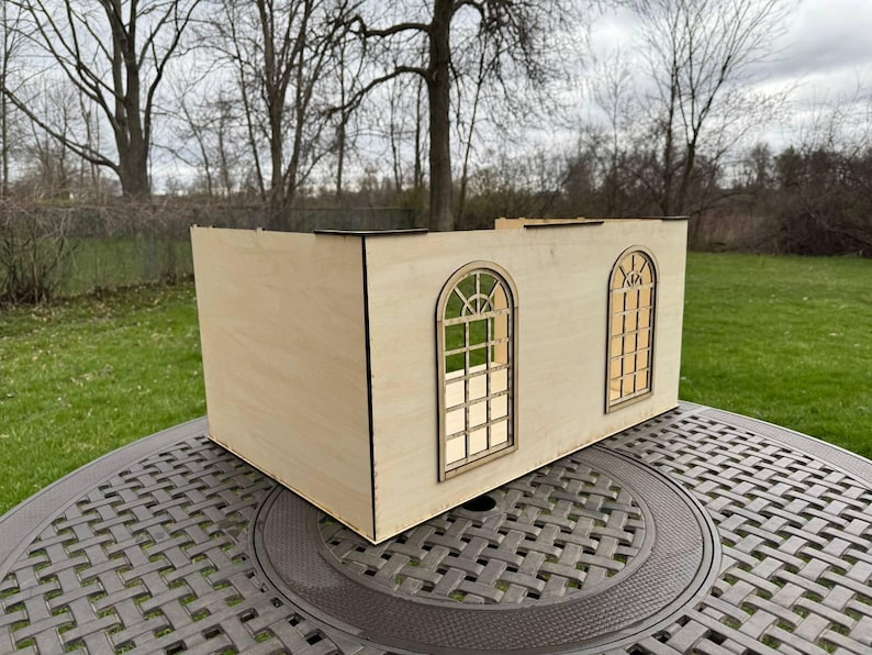 Puede incluir: Un modelo de madera de un edificio con dos ventanas arqueadas. El modelo est&aacute; hecho de madera de color claro y tiene un dise&ntilde;o simple.