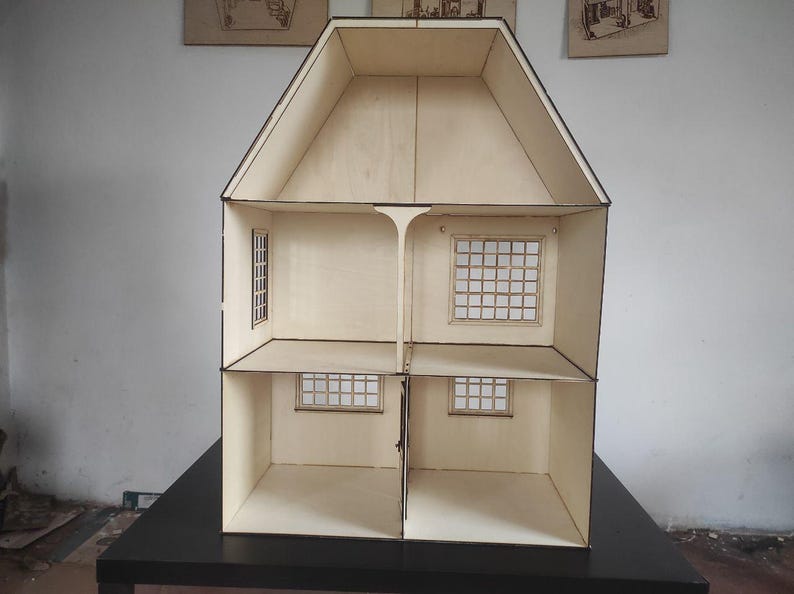 May include: A light-colored wooden dollhouse featuring a two-story structure with an attic space. The interior is divided into four rooms across two levels, each with grid-patterned windows on the walls. The exterior edges are dark-toned.