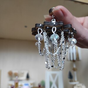 May include: A miniature wooden chandelier with silver chains and clear crystal beads.