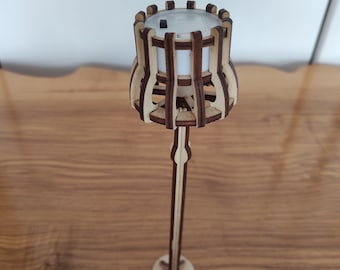 Può includere: Una lampada in legno con un design geometrico. La lampada ha una fonte di luce bianca e una base in legno marrone.