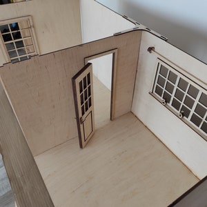May include: A wooden dollhouse room with two windows and a door. The walls are made of light wood and the floor is made of a darker wood.