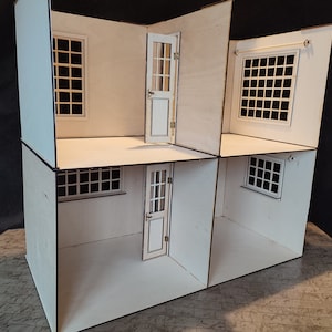 Könnte beinhalten: Ein weißes Puppenhaus mit zwei Stockwerken, vier Fenstern und zwei Türen. Das Puppenhaus ist aus Holz und hat ein schlichtes Design.