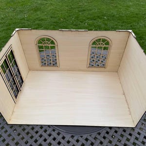 Puede incluir: Un kit de habitaci&oacute;n de casa de mu&ntilde;ecas de madera con dos ventanas y una puerta. La habitaci&oacute;n est&aacute; sin terminar y lista para ser ensamblada y decorada.