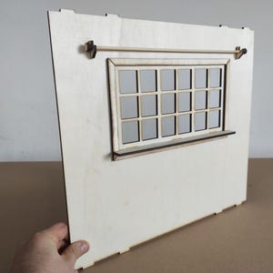 May include: A light-colored wooden wall panel for a dollhouse featuring a rectangular window with a grid of sixteen panes, a narrow horizontal shelf attached below the window frame, and a thin wooden rod mounted horizontally above the window.