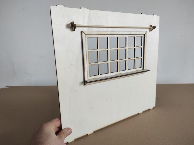 May include: A light-colored wooden wall panel for a dollhouse featuring a rectangular window with a grid of sixteen panes, a narrow horizontal shelf attached below the window frame, and a thin wooden rod mounted horizontally above the window.