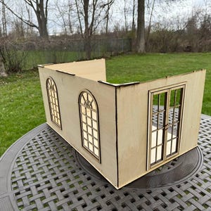 Puede incluir: Un modelo de casa de madera con dos ventanas y una puerta doble. El modelo est&aacute; hecho de madera clara y tiene un acabado natural.