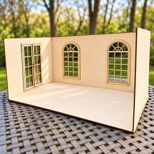 May include: A light-colored wooden dollhouse room structure featuring a flat floor, two side walls, and one back wall. The structure includes one set of double doors on the left side and two arched windows with grid panes on the back wall.