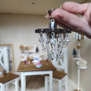 May include: A miniature chandelier with a wooden base and silver chains with crystal beads hanging from it.