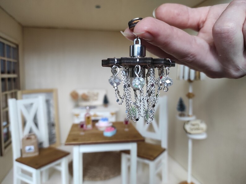 May include: A miniature chandelier with a wooden base and silver chains with crystal beads hanging from it.