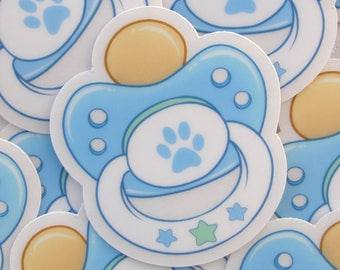 May include: A close-up of several blue and white pacifier stickers with a paw print design. The stickers are arranged in a random pattern.