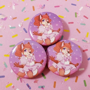 May include: Three 2.25 inch button pins featuring a cartoon fox wearing a pink dress and a bow. The fox has red hair and brown eyes. The background of the buttons is purple with white stars.